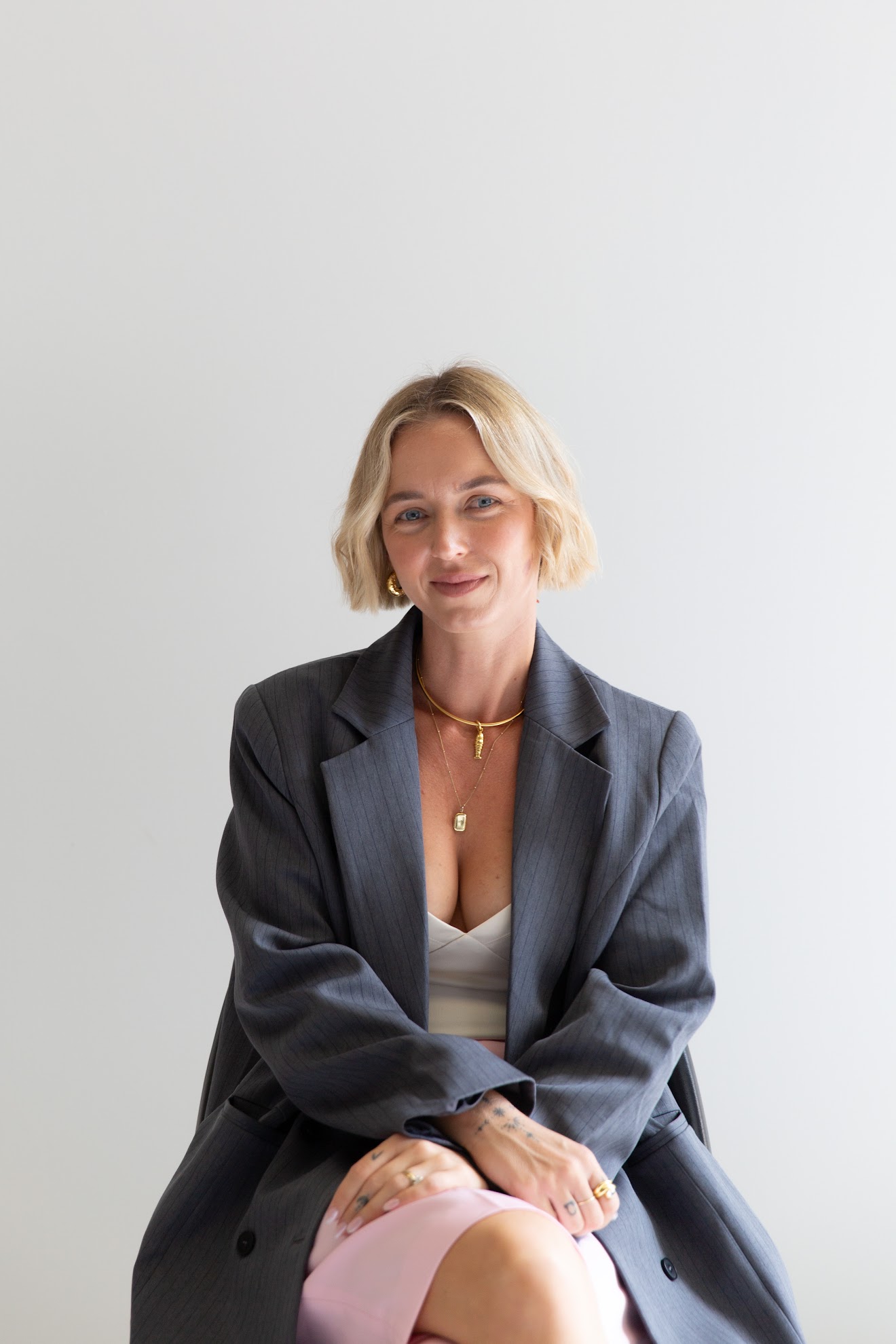 Missy Holliday seated in a charcoal blazer and pink skirt